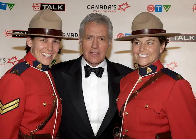 El presentador del programa de juegos de televisi&oacute;n Alex Trebek (C) posa con las Mounties canadienses Mia Poscente (L) y April Dequanne en el backstage en la novena ceremonia anual del Paseo de la Fama de Canad&aacute; en Toronto. / EFE / WARREN TODA
