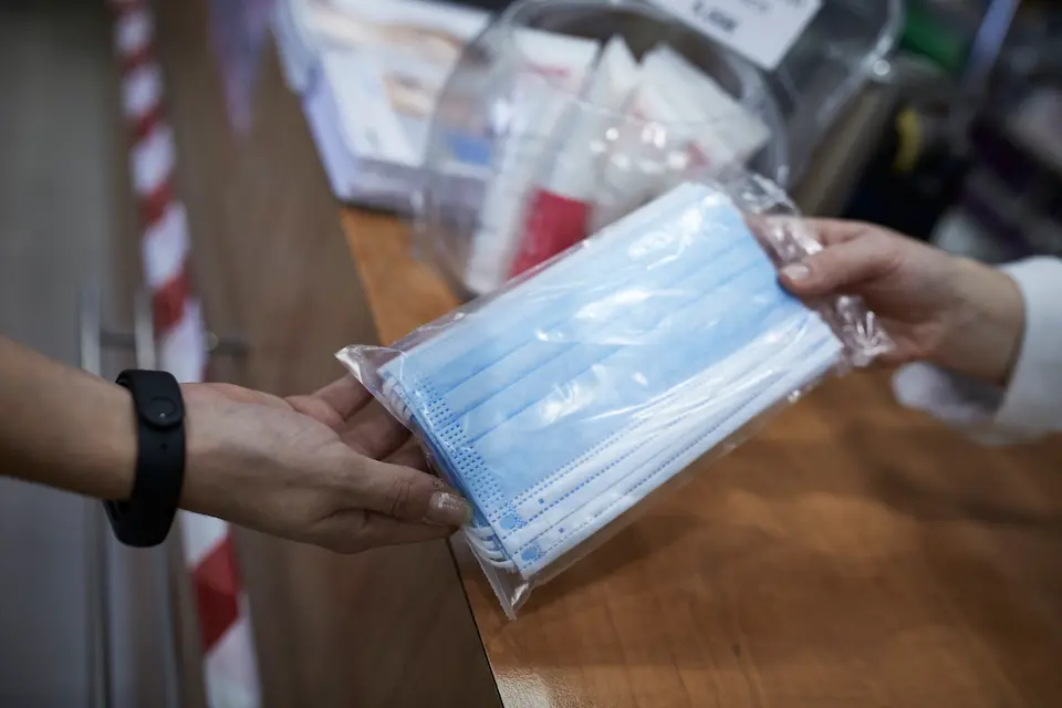 Una farmac&eacute;utica ense&ntilde;a a un cliente un paquete de mascarillas. / ALERTA