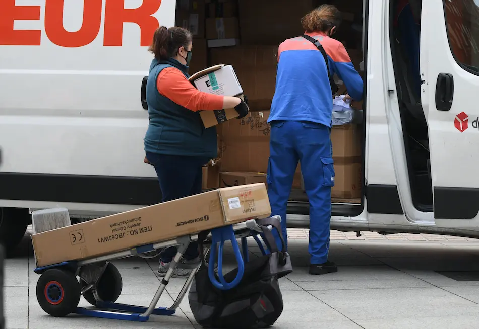 Dos trabajadores de reparto durante su jornada en la ciudad de Santander. / HARDY