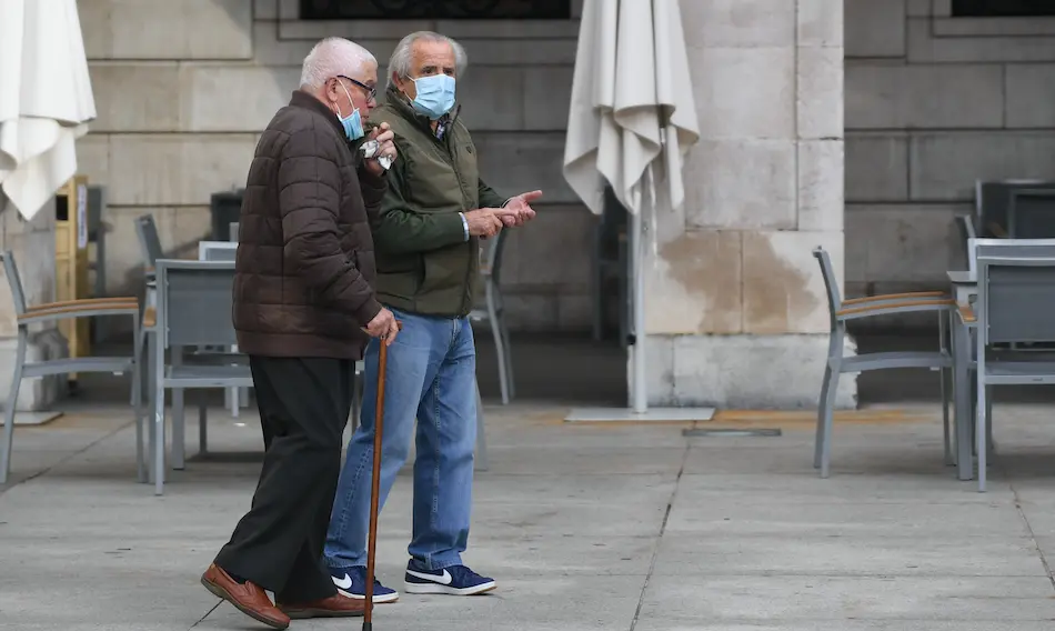 Dos personas de avanzada edad pasean por la plaza Porticada de Santander. / HARDY