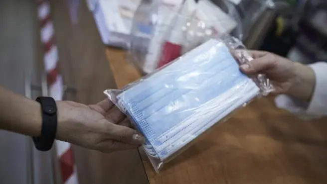 Una farmace&uacute;tica entrega un paquete de mascarillas. / ALERTA