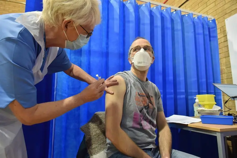 David Farrell, paciente de 51 a&ntilde;os, recibe una de las dos vacunas de Pfizer y BioNtech en un centro de vacunaci&oacute;n hoy, en Cardiff (Reino Unido). El Reino Unido inici&oacute; el mayor programa de inmunizaci&oacute;n de la historia del pa&iacute;s. Los trabajadores a domicilio, el personal del NHS y las personas de 80 a&ntilde;os o m&aacute;s comenzar&aacute;n a recibir la vacuna contra el coronavirus. EFE/Ben Birchal/ POOL