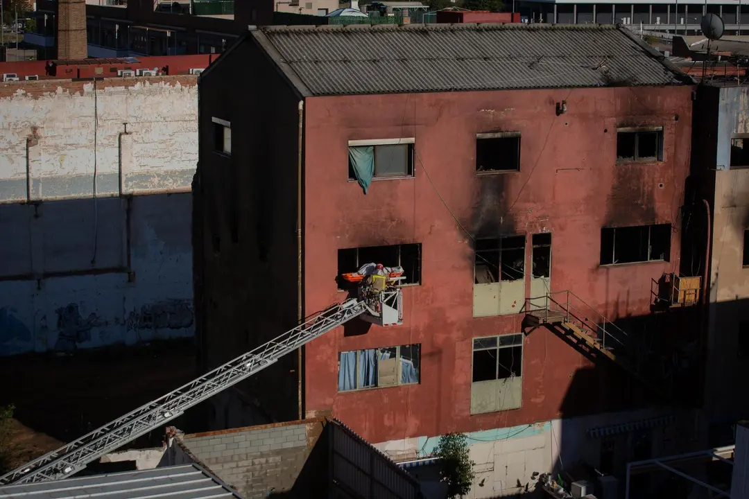 Bomberos retiran el cad&aacute;ver de una de las personas fallecidas en el incendio. / E. PRESS