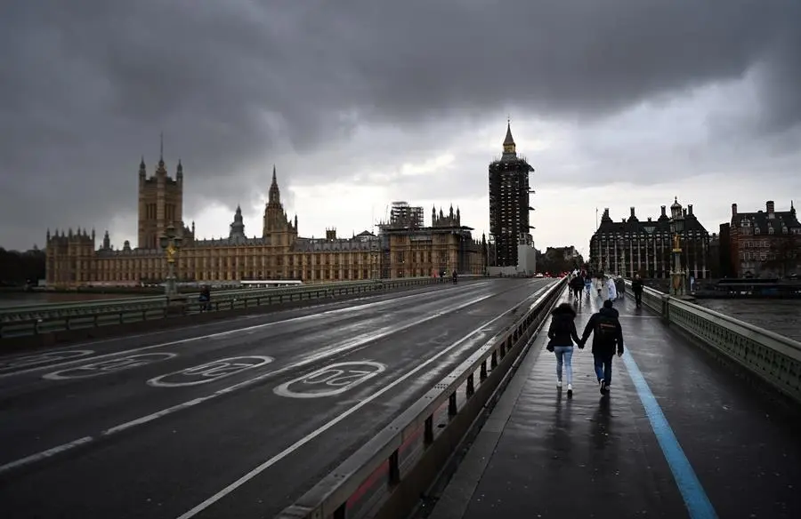 Varias personas cruzan el puente de Westminster, este lunes en Londres (Reino Unido), cuando las autoridades brit&aacute;nicas se est&aacute;n planteando un nuevo cierre de tiendas de ropa, bares y restaurantes en la capital ante el nuevo repunte de positivos por coronavirus. EFE/ Andy Rain