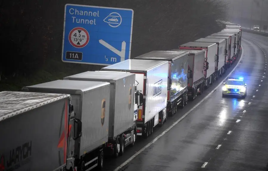 Un coche de polic&iacute;a pasa junto a una larga cola de camiones que permanecen atrapados a causa del cierre de la frontera con Reino Unido decretada por Francia, este lunes en Kent, Reino Unido. EFE/Neil Hall