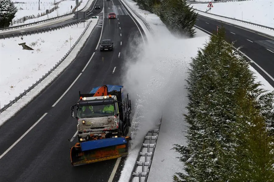 Una m&aacute;quina quitanieves limpia la A-67 tras una nevada por la que varios camiones permanecen en un atasco este s&aacute;bado en la localidad c&aacute;ntabra de Arenas de Igu&ntilde;a. EFE/Pedro Puente Hoyos