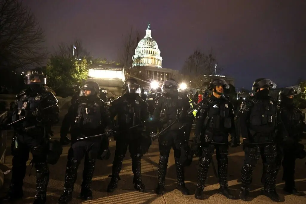 Oficiales de polic&iacute;a con equipo antidisturbios se alinean frente al Capitolio despu&eacute;s de ser invadido por una turba violenta. Tasos Katopodis/Getty Images