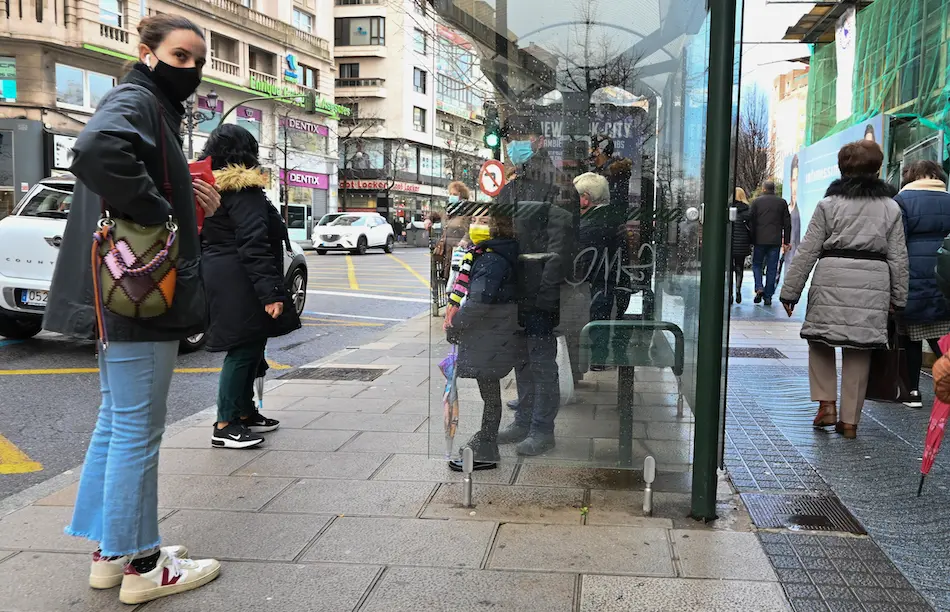 Varias personas con mascarilla en una parada de autob&uacute;s en el centro de Santander. / Hardy