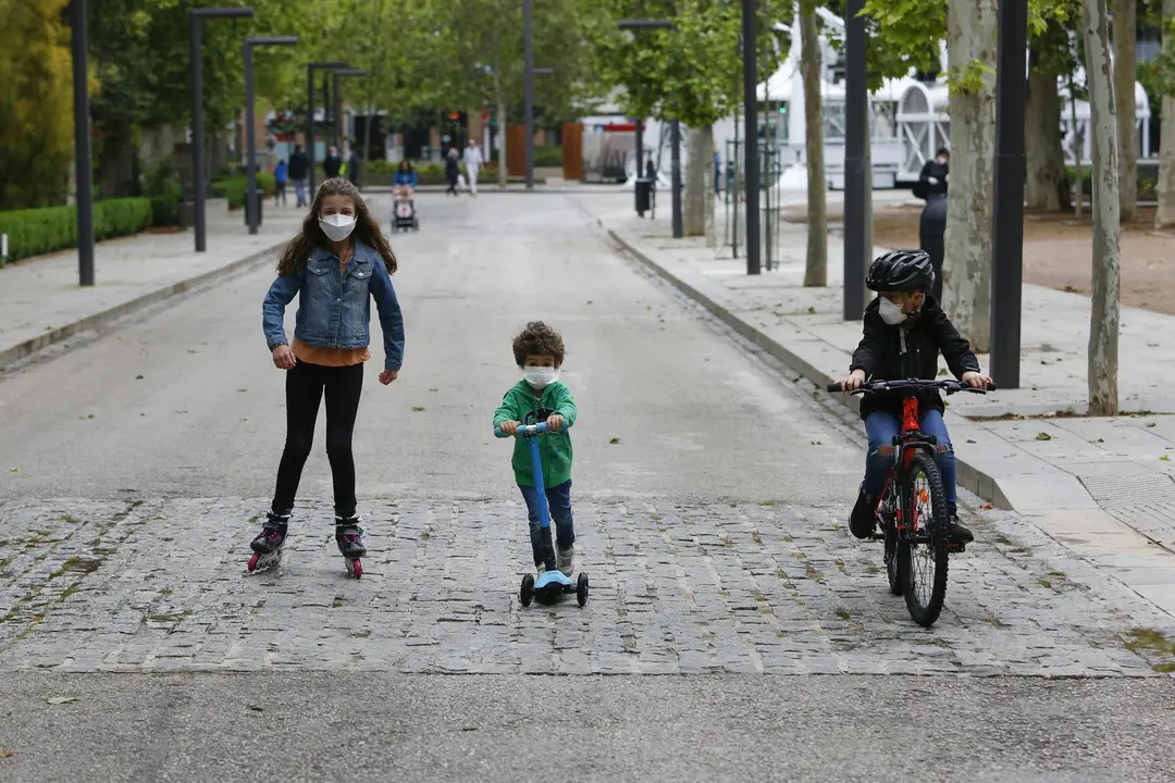 Tres ni&ntilde;os practican deporte al aire libre protegidos con mascarillas