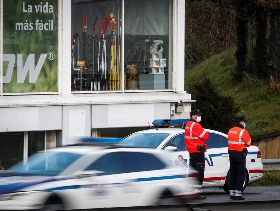 Dos agentes de la Ertzaintza realizan un control en la salida de la localidad guipuzcoana de Andoain, uno del total de 20 municipios vascos, 11 de ellos de m&aacute;s de 5.000 habitantes, quedar&aacute;n confinados perimetralmente a partir de este viernes y tendr&aacute;n la hosteler&iacute;a cerrada al situarse actualmente en "zona roja" por su alta tasa de contagios de coronavirus. EFE/Javier Etxezarreta