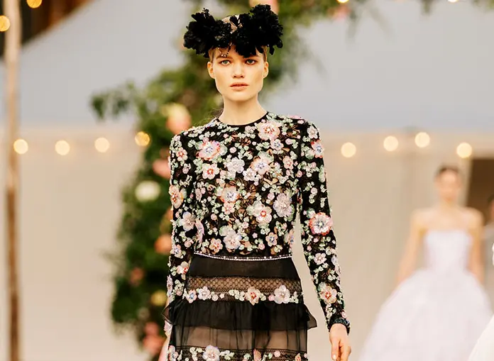 Chanel abri&oacute; la pasarela un conjunto de encaje con blusa blanca de mangas francesas y falda bohemia hasta los pies en un llamativo rosa, un contraste de colores pensado para alegrar el ambiente.