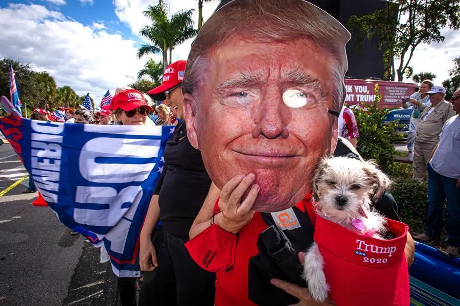 Una persona sostiene una m&aacute;scara con la imagen del presidente Donald Trump mientras espera su llegada este mi&eacute;rcoles en West Palm Beach al sureste de Florida. Donald Trump lleg&oacute; este mi&eacute;rcoles todav&iacute;a como presidente de EE.UU. a Palm Beach (sureste de Florida), antes de la asunci&oacute;n presidencial de Joe Biden en Washington, a bordo del avi&oacute;n Air Force One procedente de la base a&eacute;rea Andrews, en Maryland, a las afueras de Washington. EFE/Giorgio Viera