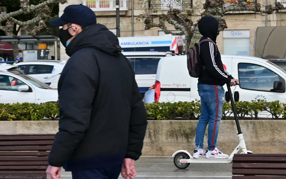 Dos personas con mascarilla por el paseo Pereda, mientras cruza a toda velocidad una ambulancia. / Hardy