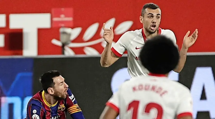 Leo Messi  cae ante el centrocampista del Sevilla, Joan Jord&aacute;. / Julio Mu&ntilde;oz