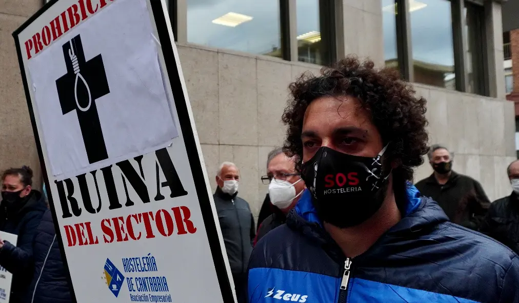 Un hostelero sostiene un cartel de denuncia ante la Consejer&iacute;a de Sanidad en la &uacute;ltima manifestaci&oacute;n del sector. / HARDY