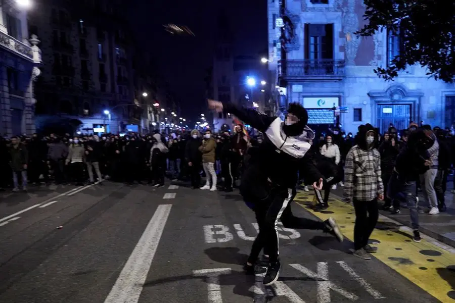Manifestantes lanzan objetos esta noche frente a la comisar&iacute;a de V&iacute;a Layetana, en el centro de Barcelona, en una nueva manifestaci&oacute;n por la libertad de Pablo Hasel, despu&eacute;s de cinco d&iacute;as consecutivos de protestas que han finalizado con enfrentamientos con los Mossos d'Esquadra y da&ntilde;os a bienes p&uacute;blicos y privado. EFE/Alejandro Garc&iacute;a
