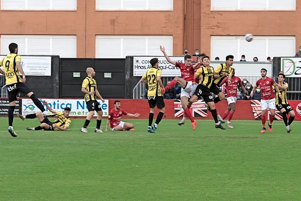 Un jugador del Laredo trata de rematar la pelota ante la oposici&oacute;n de los jugadores del Portugalete. / Reguera