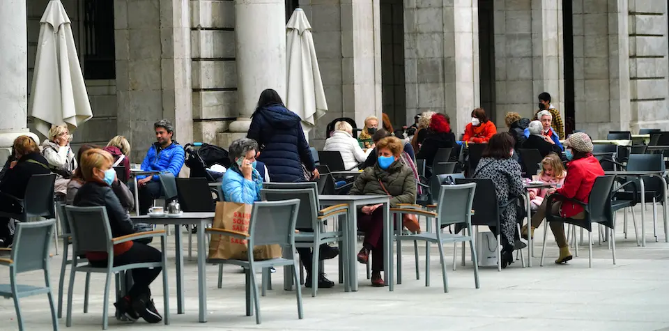 Varias personas con mascarilla disfrutan de la terraza de un establecimiento de hosteler&iacute;a en la plaza Porticada de Santander. / HARDY