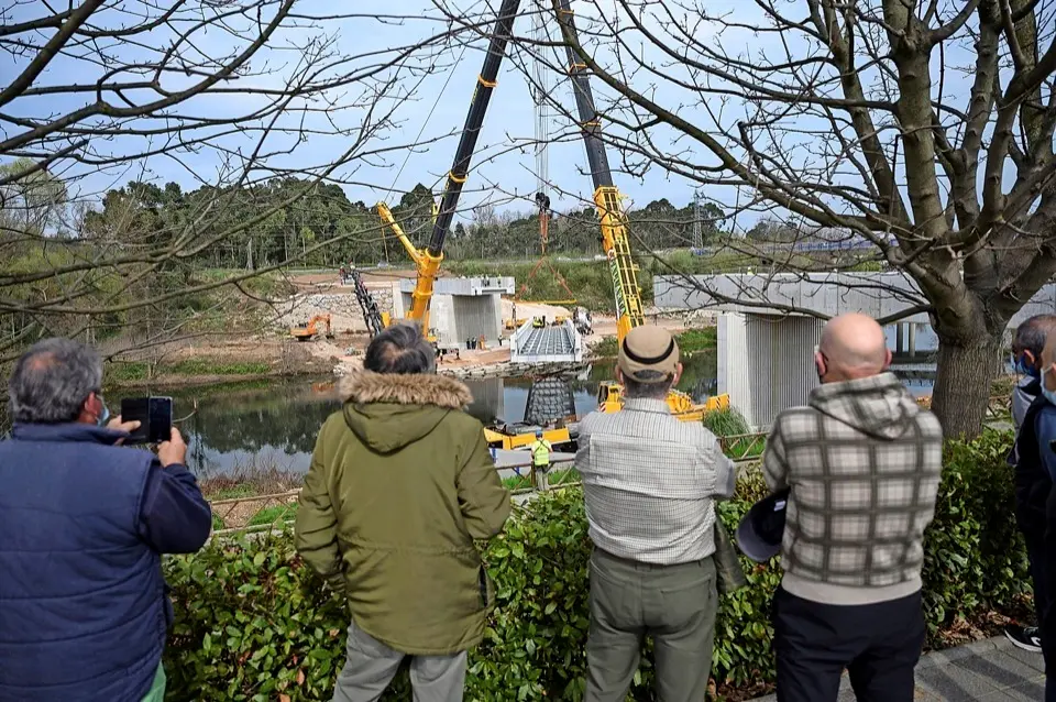 Varias personas observan los trabajos en la futura pasarela sobre el r&iacute;o Besaya en Torrelavega. / PEDRO PUENTE HOYOS