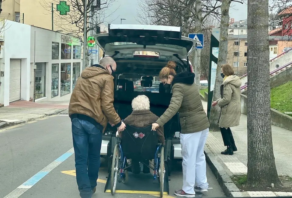 Dos personas personas ayudan a una mujer de avanzada edad a bajar del veh&iacute;culo en Santander. / Hardy