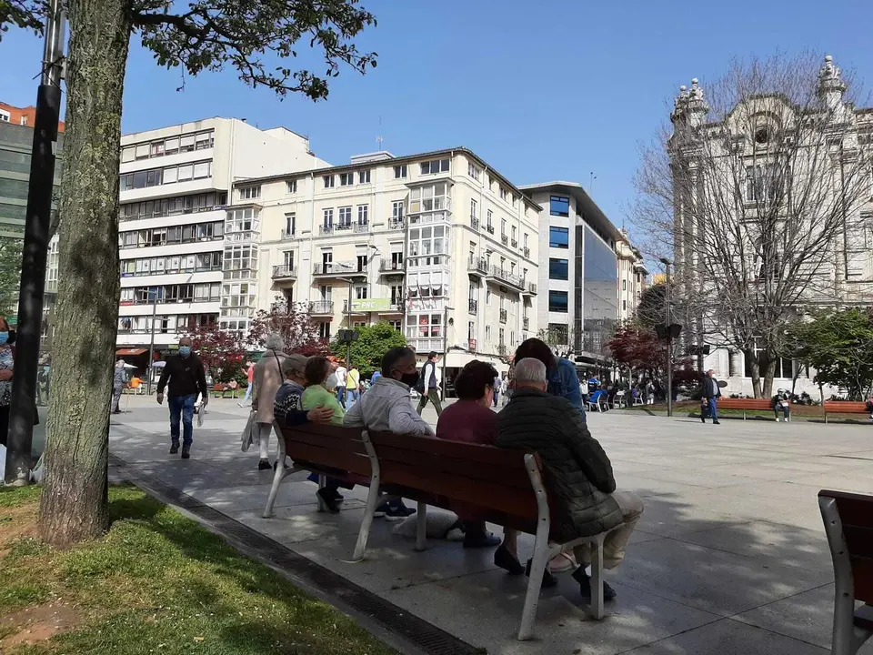 Varias personas sentadas en los bancos de la plaza del Ayuntamiento de Santander. / S. D&iacute;az