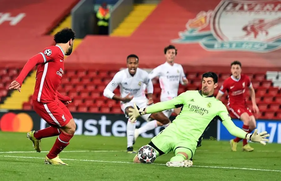 Liverpool's Mohamed Salah (L) en acci&oacute;n contra el portero del Real Madrid Thibaut Courtois (R) durante los cuartos de final de la Liga de Campeones de la UEFA, segundo partido de f&uacute;tbol entre el Liverpool FC y el Real Madrid en Liverpool, Reino Unido, 14 de abril de 2021. (Liga de Campeones, Reino Unido) EFE / EPA / Peter Powell