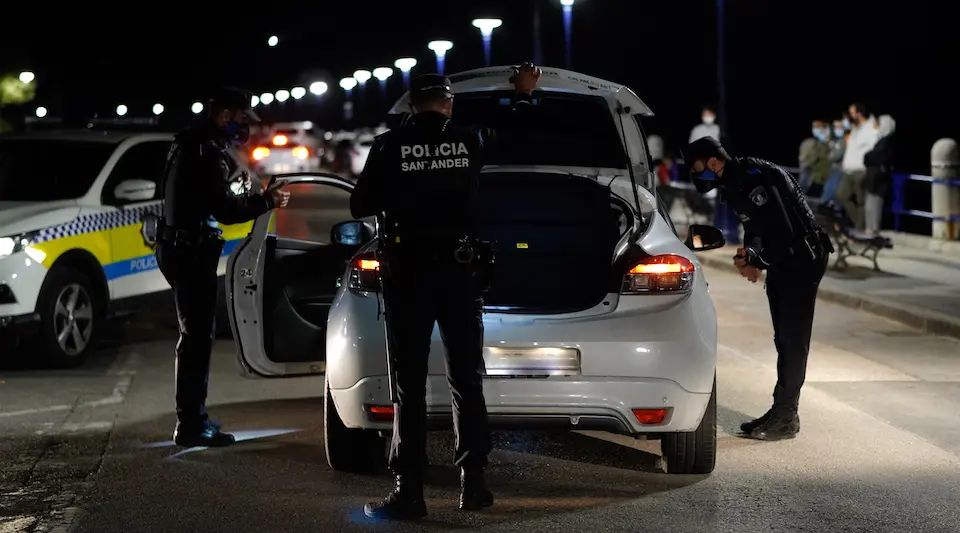 Varios polic&iacute;as revisan un coche durante el primero d&iacute;a sin el estado de alarma en el parking de la playa El Camello. / HARDY