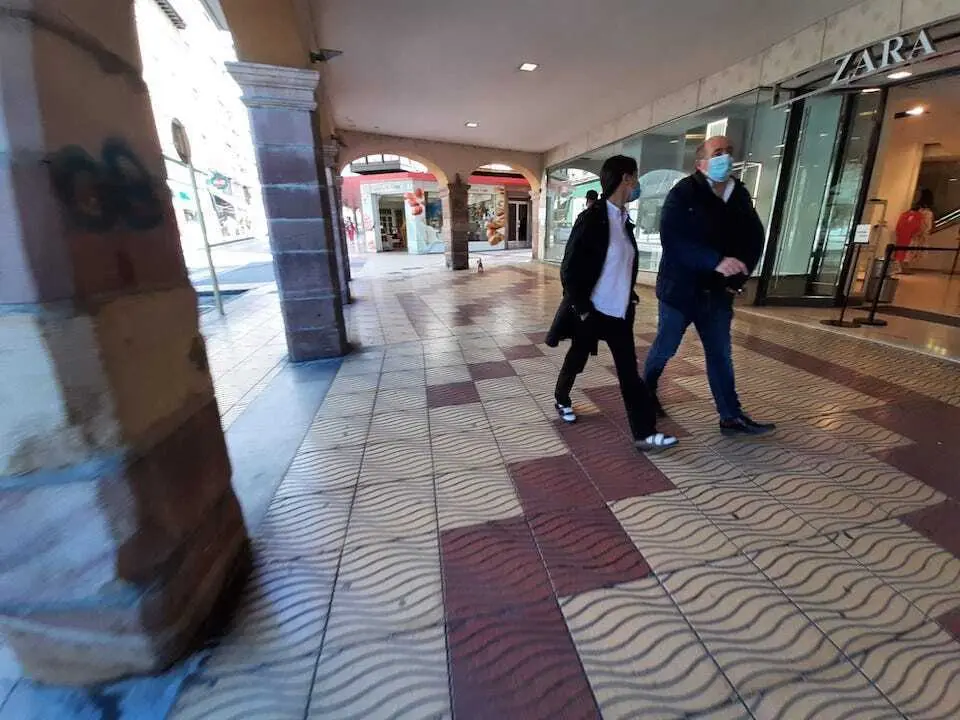 Varios torrelaveguenses con mascarilla por los soportales comerciales del centro de la ciudad.