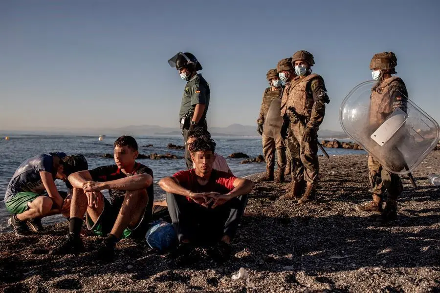 Miembros del ej&eacute;rcito observan a un grupo de inmigrantes menores a su llegada a la playa de El Tarajal en Ceuta este mi&eacute;rcoles. La frontera de Ceuta entre Marruecos y Espa&ntilde;a ha amanecido con solo unas decenas de inmigrantes que intentan llegar a nado, una situaci&oacute;n que difiere de la registrada hace dos d&iacute;as, cuando llegaron 8.000 personas, la mitad de las cuales han sido devueltas, seg&uacute;n el Gobierno espa&ntilde;ol. EFE/Brais Lorenzo