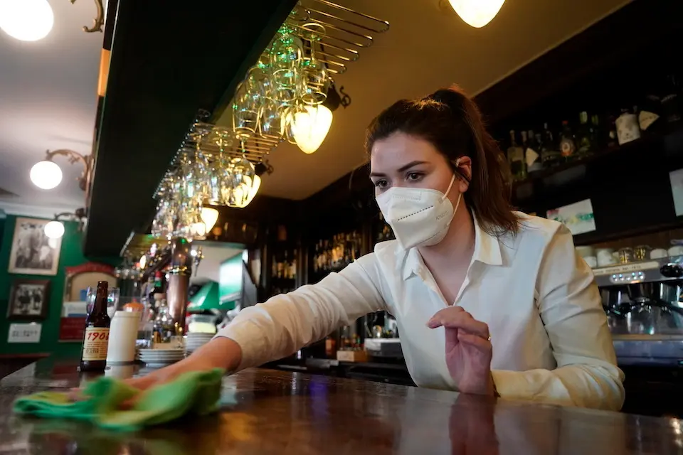 Una trabajadora de la hosteler&iacute;a repasa la barra del local tras el primer d&iacute;a del incremento del cierre. / HARDY