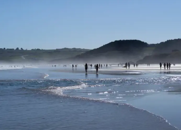 Varias personas caminan por una playa c&aacute;ntabra.