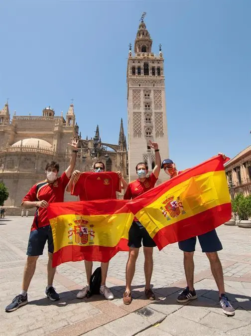 Aficionados de la selecci&oacute;n de Espa&ntilde;a delante de la Giralda y la Catedral en el centro de Sevilla antes del debut de Espa&ntilde;a frente a Suecia en esta Eurocopa 2020, que se jugar&aacute; hoy en el Estadio Ol&iacute;mpico de La Cartuja. EFE/ Ra&uacute;l Caro.
