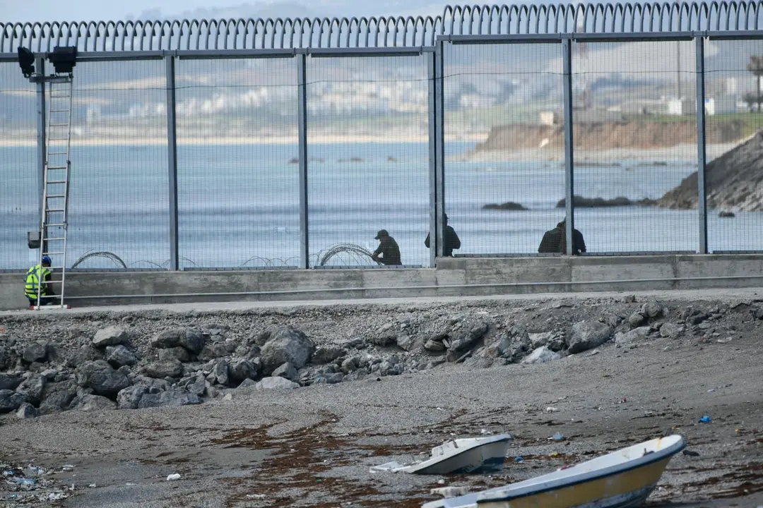 Agentes de la Gendarmer&iacute;a Real marroqu&iacute; y Fuerzas auxiliares (Mejania) levantan alambradas de concertinas en la parte inferior del vallado en el espig&oacute;n del Tarajal, a 1 de junio de 2021
