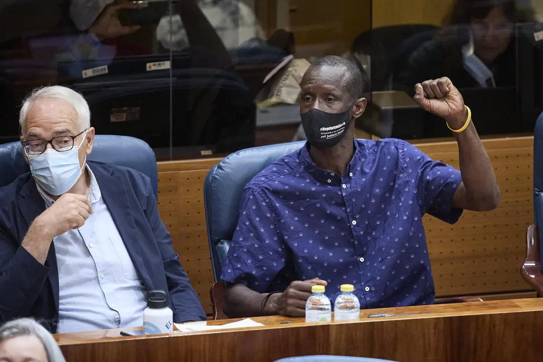 El portavoz del sindicato de manteros y miembro de la Asociaci&oacute;n de los Sin Papeles, Serigne Mbaye levanta el brazo para pedir la palabra por alusiones