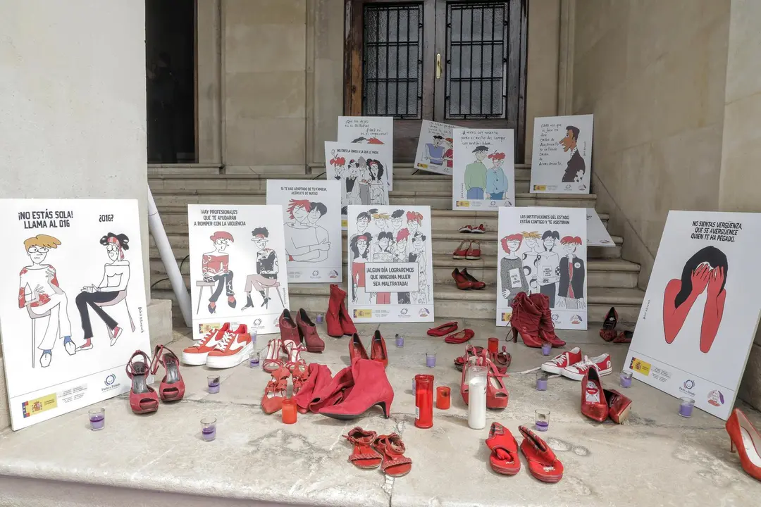 Varios pares de zapato de color rojo, velas y carteles contra la violencia contra las mujeres a las puertas de la Subdelegaci&oacute;n del Gobierno en Alicante, donde hoy se ha guardado un minuto de silencio en repulsa del asesinato machista de Wafaa Sebbah, 