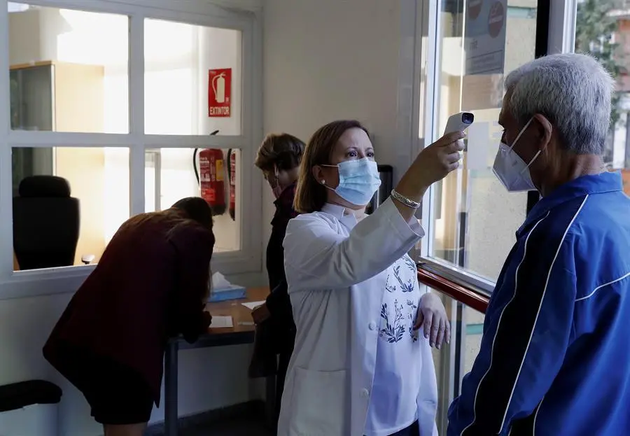 Una trabajadora toma la temperatura a un usuario a las puertas de un centro de mayores, este lunes, d&iacute;a de reapertura de estos centros en la Comunidad de Madrid. EFE/JP Gandul