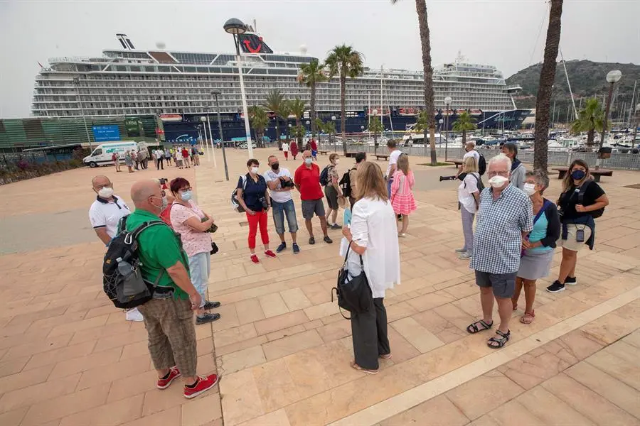 Un grupo de turistas alemanes del "Mein Schiff 2", el primer crucero que atraca en el Puerto de Cartagena tras la suspensi&oacute;n del turismo mar&iacute;timo desde marzo de 2020 a causa de la pandemia del coronavirus, atiende a las explicaciones de una gu&iacute;a tur&iacute;stica este s&aacute;bado. El "Mein Schiff 2" lleg&oacute; hoy a Cartagena con unos mil turistas alemanes a bordo procedentes de Palma de Mallorca. EFE/Marcial Guill&eacute;n