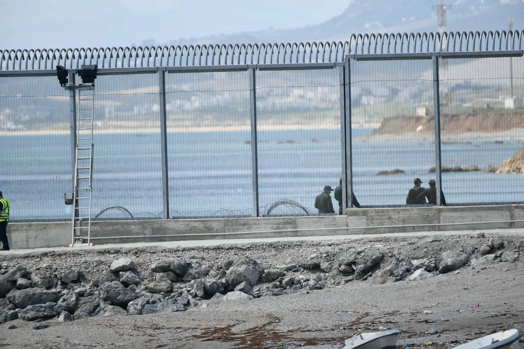 Agentes de la Gendarmer&iacute;a Real marroqu&iacute; y Fuerzas auxiliares (Mejania) levantan alambradas de concertinas en la parte inferior del vallado en el espig&oacute;n del Tarajal, a 1 de junio de 2021, en Marruecos.