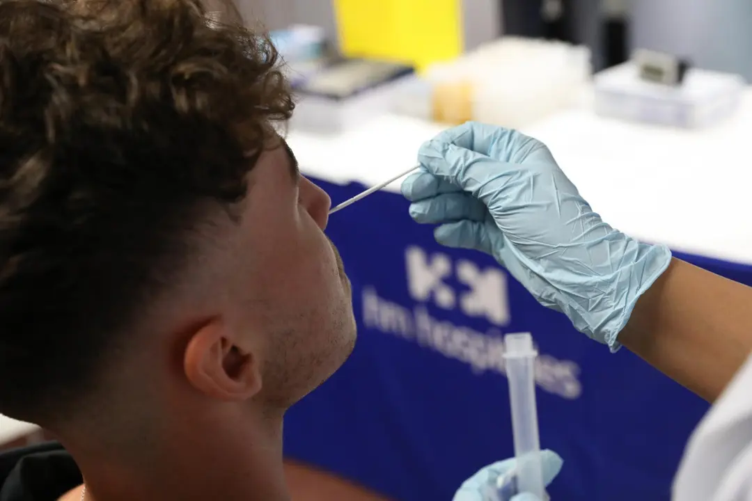 Un sanitario realiza un test de ant&iacute;genos a un hombre.