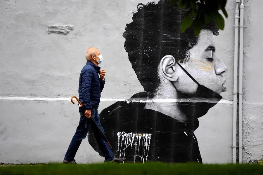 Un hombre con mascarilla camina delante de una obra del artista @Sentydo ART en una campa&ntilde;a dedicada a los besos sin mascarillas. Desde el colectivo "El VeSu" reivindican esta acci&oacute;n : "Desde el VeSu no solo queremos empapar Oviedo de cultura, tambi&eacute;n queremos recuperar el tiempo perdido en estos &uacute;ltimos meses. Todos esos besos que no hemos podido dar a la gente que m&aacute;s queremos, los abrazos, las miradas, los verm&uacute;s que llegan hasta la noche". EFE/ Eloy Alonso