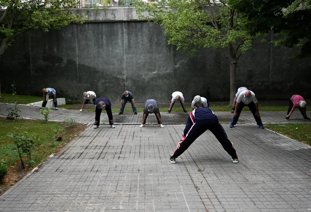 Un grupo de ancianos realiza ejercicio en el jard&iacute;n de un centro de d&iacute;a de personas mayores de la Comunidad de Madrid