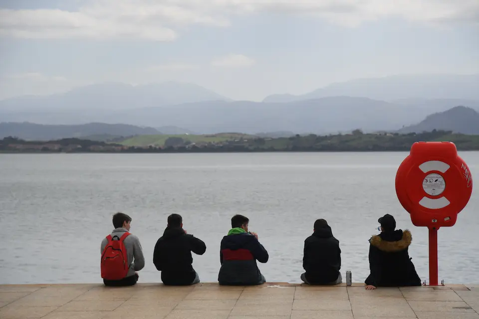 Varios j&oacute;venes sentados frente a la bah&iacute;a de Santander. / Hardy