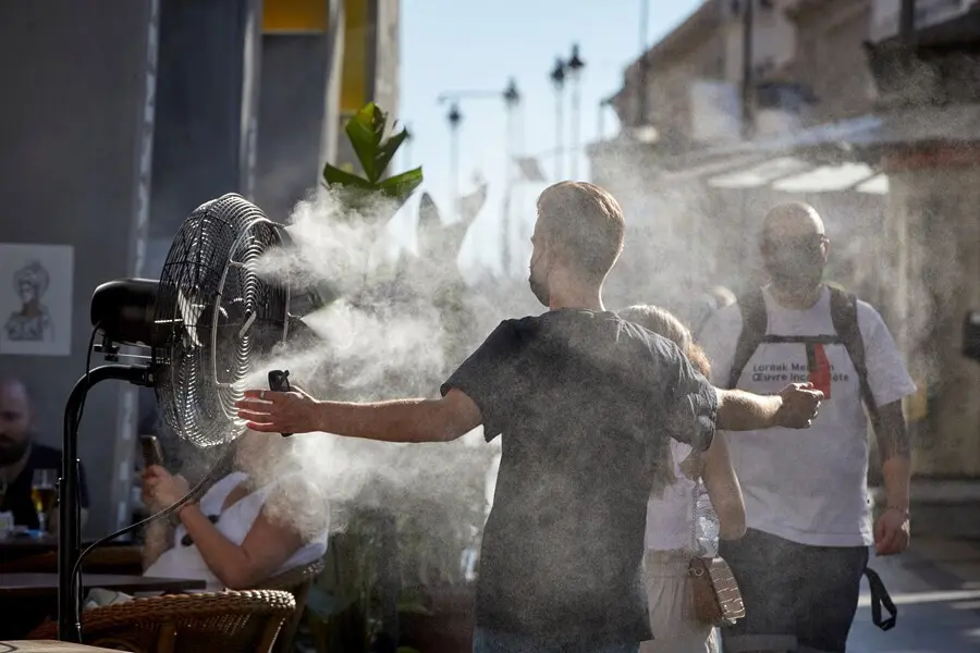 Un chico se refresca del calor con un difusor de vapor de agua de un restaurante de la calle Alcal&aacute;, en Madrid