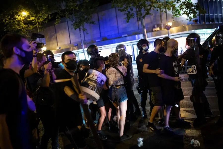 Una joven se enfrenta a antidisturbios de la Polic&iacute;a Nacional en el barrio de Arg&uuml;elles tras la concentraci&oacute;n por el asesinato del joven Samuel