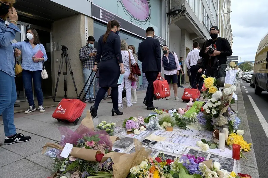 Varias personas pasan al lado del altar colocado en la acera donde fue golpeado Samuel, el joven asesinado en A Coru&ntilde;a el pasado s&aacute;bado 3 de julio.