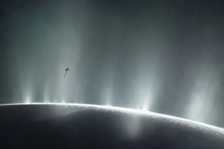 La impresi&oacute;n de este artista muestra la nave espacial Cassini de la NASA volando a trav&eacute;s de una columna de supuesta agua que brota de la superficie de Encelado, la luna de Saturno.