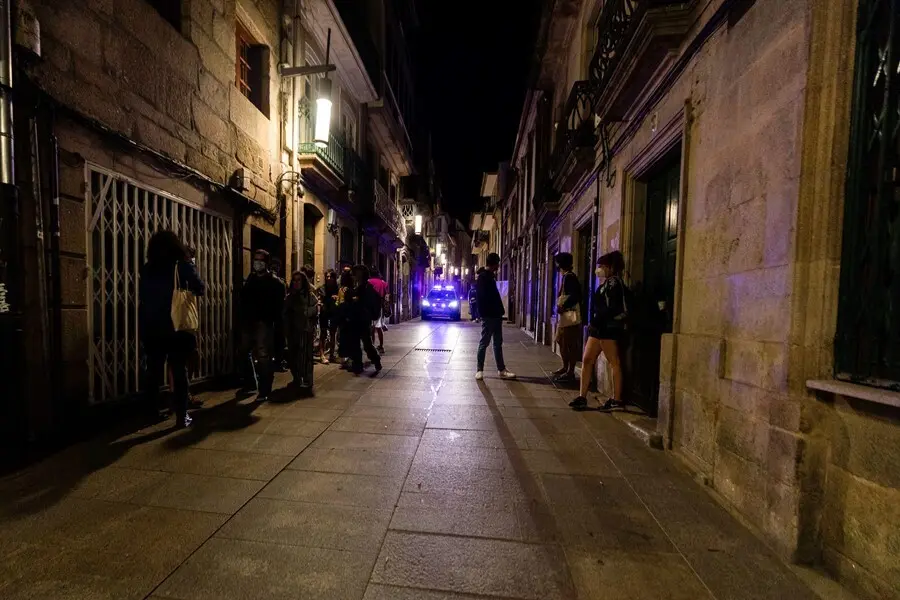 Un coche de polic&iacute;a pasa frente a varias personas en ambiente festivo, a 10 de julio de 2021, en Pontevedra, Galicia (Espa&ntilde;a)