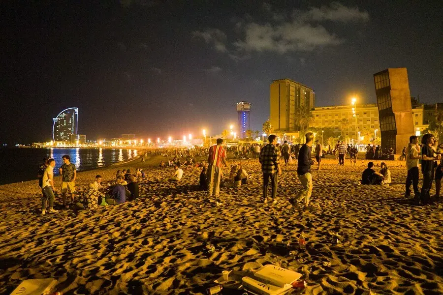 J&oacute;venes se re&uacute;nen en la playa de la Barceloneta horas antes de que entre en vigor el toque de queda en Catalunya