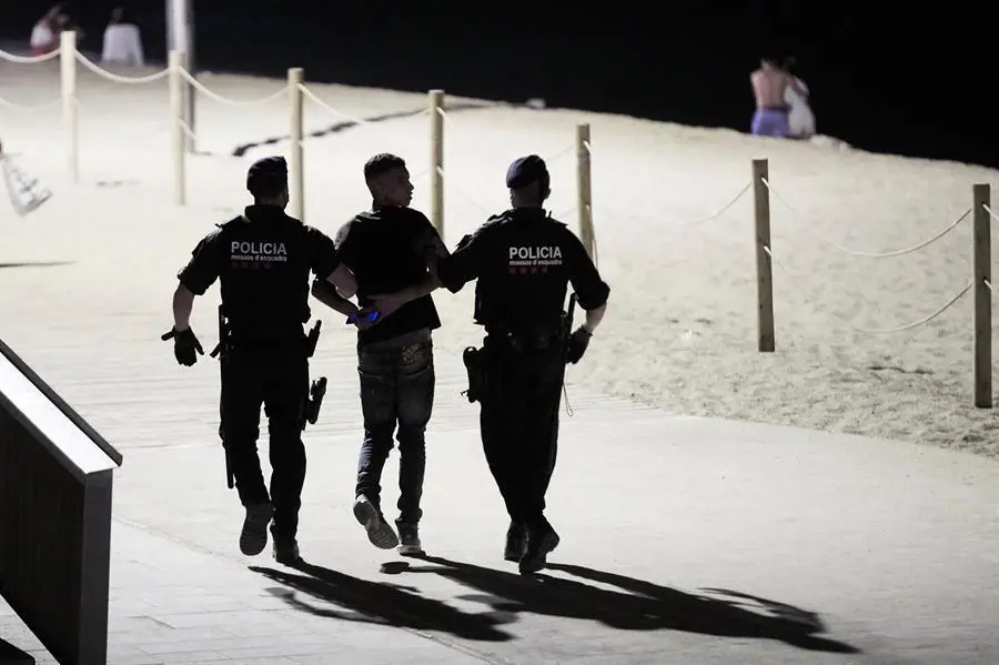 Agentes de los Mossos de Escuadra detienen a uno de los j&oacute;venes implicados en una pelea que se ha producido hoy viernes en la playa de la barceloneta, en la noche que entra el toque de queda nocturno, desde la 1 de la madrugada a 6 de la ma&ntilde;ana, en los 161 municipios afectados por esta nueva restricci&oacute;n que ha autorizado el Tribunal Superior de Justicia de Catalu&ntilde;a (TSJC) hasta el 23 de julio. EFE/Alejandro Garc&iacute;a.