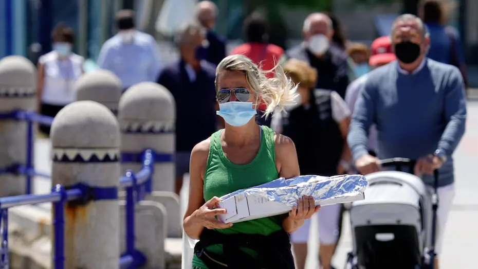 Varias personas con mascarilla transitan por las inmediaciones de la playa del Sardinero en Santander. / Hardy